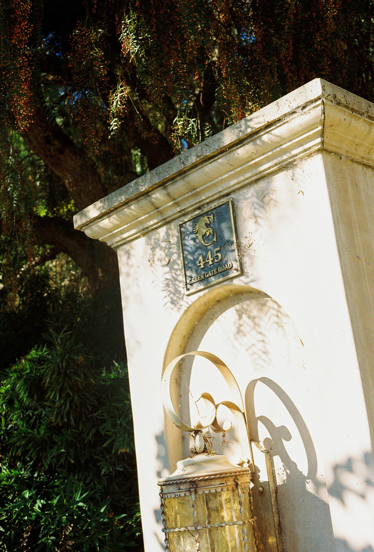 The white entry gate pillar at 445 Green Gate Road, marked with a hand-tiled address plaque and lantern