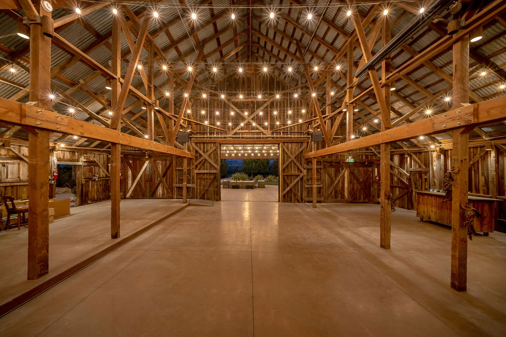 The Cavalli Estates event barn glowing with hundreds of string lights at dusk